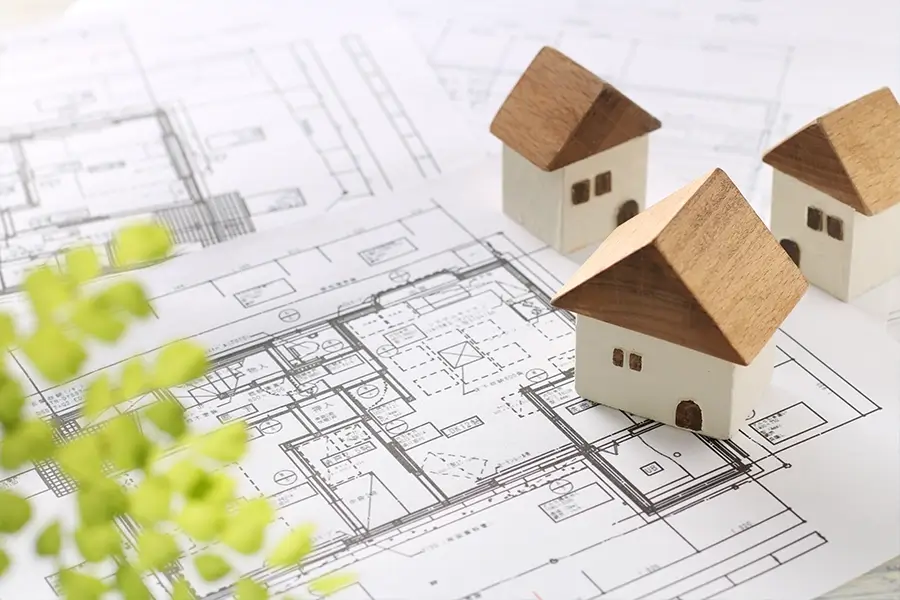 図面の上に乗った家の模型の写真